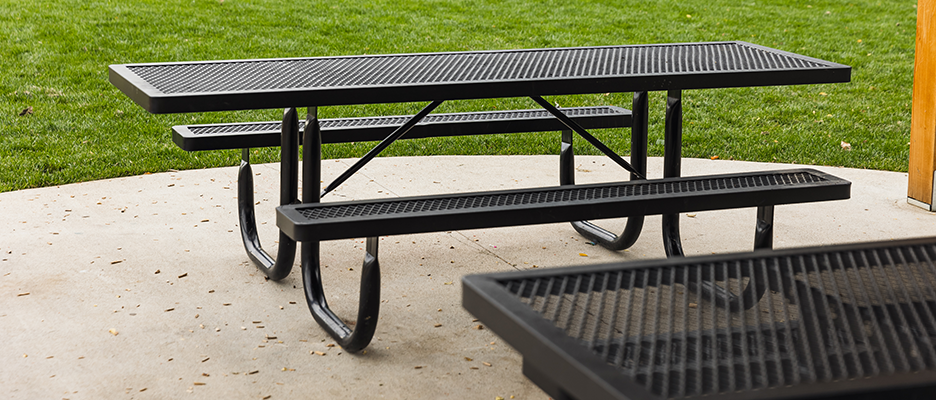 Commercial thermoplastic picnic table with Walk-Through style legs and perforated metal top installed on a concrete pad